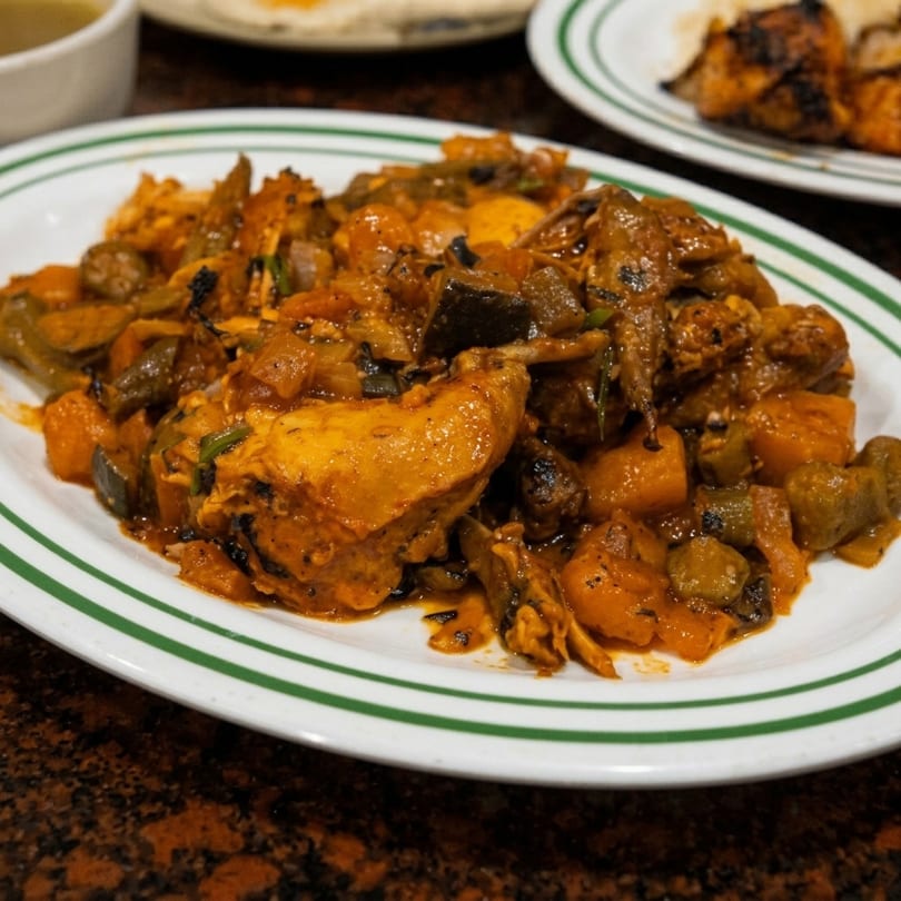 Close-up of a plate of chicken and vegetable stew with a rich, savory sauce.