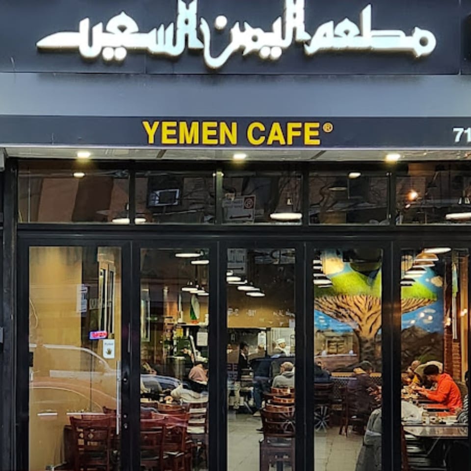 Exterior of Yemen Cafe & Restaurant with its sign and customers visible through the windows.