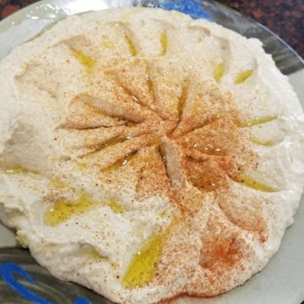 Creamy hummus with a swirl design, drizzled with olive oil and sprinkled with paprika.