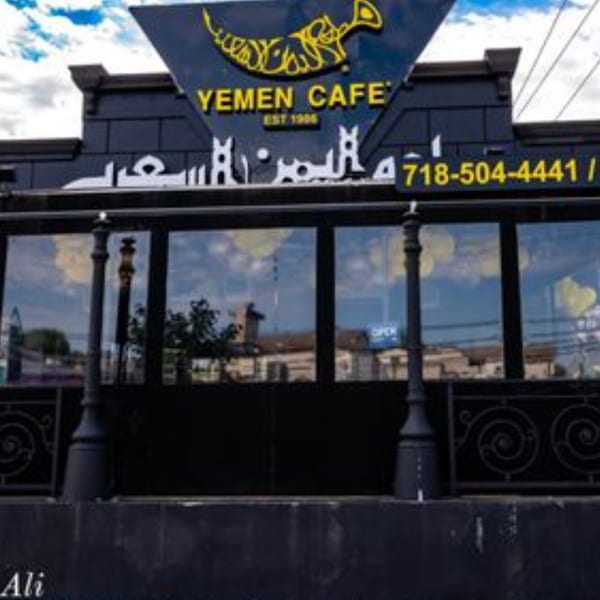 Exterior of Yemen Cafe & Restaurant with its black facade, yellow sign, and large windows.