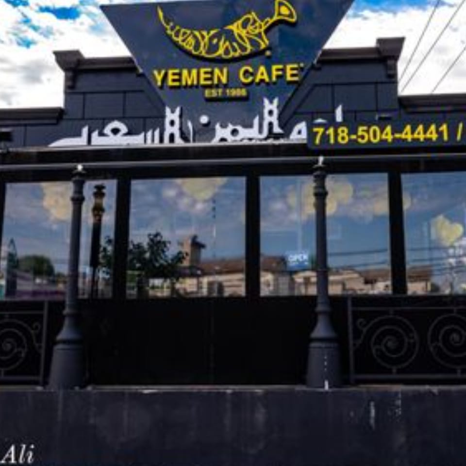 Exterior of Yemen Cafe & Restaurant with its black facade, yellow sign, and large windows.