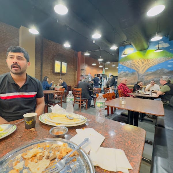 Diners enjoying Middle Eastern food at Yemen Cafe & Restaurant, with a man in the foreground.