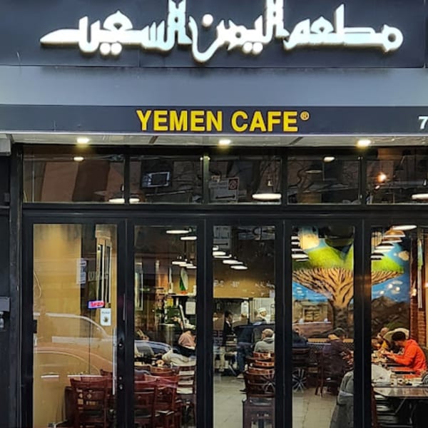 Exterior of Yemen Cafe & Restaurant with its sign and customers visible through the windows.