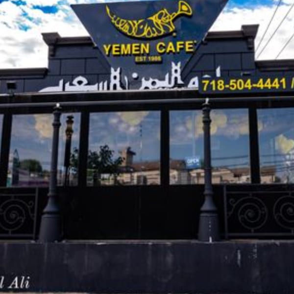 Exterior of Yemen Cafe & Restaurant, a black building with large windows and yellow signage.